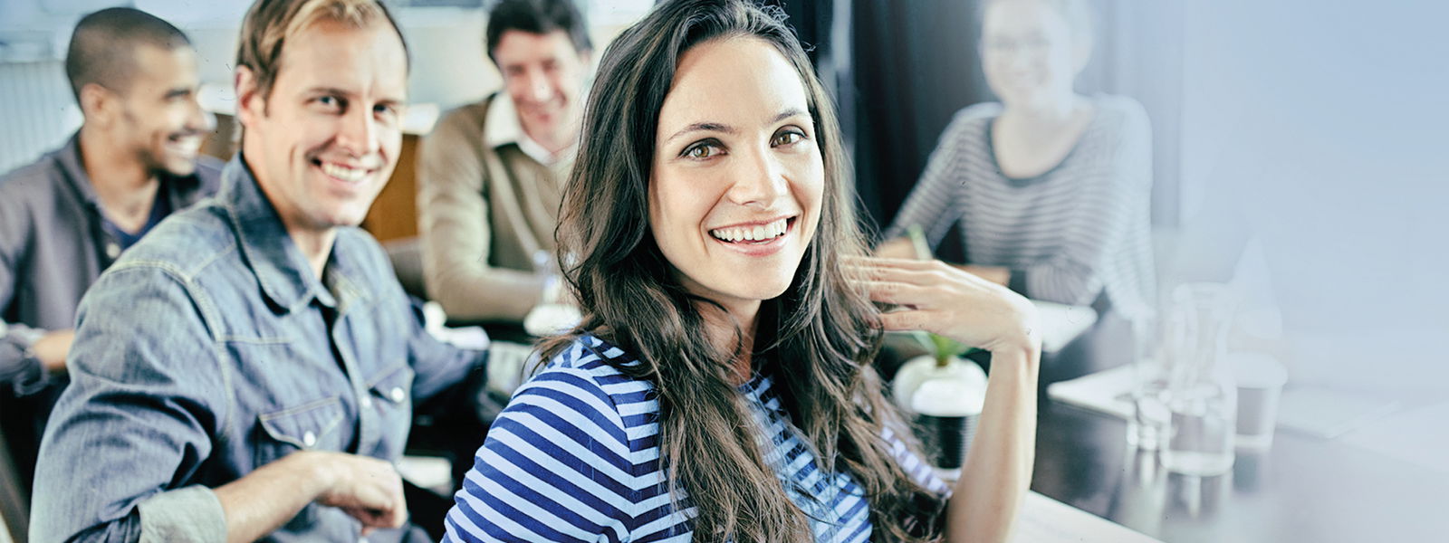 Eine Gruppe von jungen Personen sitzen an einem Tisch und lächeln.