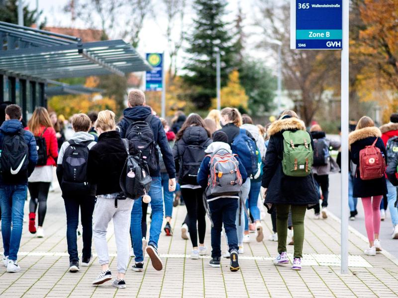 Schülerinnen und Schüler gehen mit ihren Schulrucksäcken von einer Bushaltestelle zu ihrer Schule in Niedersachsen. Foto: Hauke-Christian Dittrich/dpa